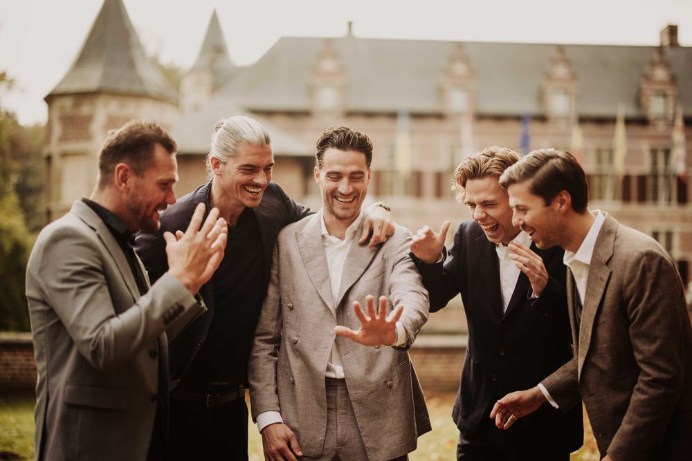 Bruidegom en vrienden lachen voor een kasteel