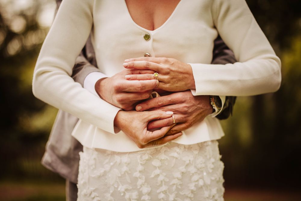 Handen met trouwringen op de jurk